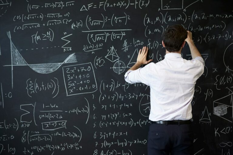 The instructor is writing formulas on the blackboard.