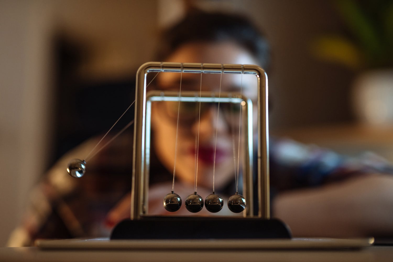 The student in the background is looking at a Newton's cradle in the Correlational Methods course.